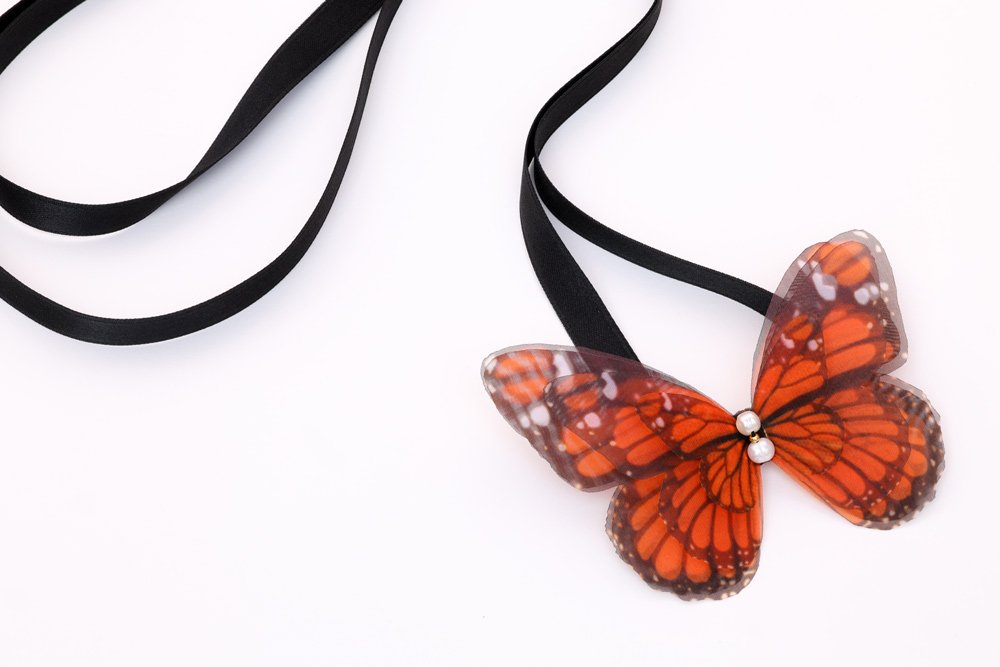 Butterfly Ribbon Tie - Monarch, Black Ribbon Oana Savu Handmade ribbon tie accessory is sewn by hand in our little atelier near in Antwerp, Belgium. The voluminous silk butterfly worn around your neck, frames the face, adding a spark of ingenuity to any look. It is sewn on a high-quality silk satin ribbon tie, with a customizable length to fit more styles, worn around your neck - as a choker necklace, style your hair oh hot summer days, around your wrist as a bracelet or even around your waist as a belt for those light summer dresses.