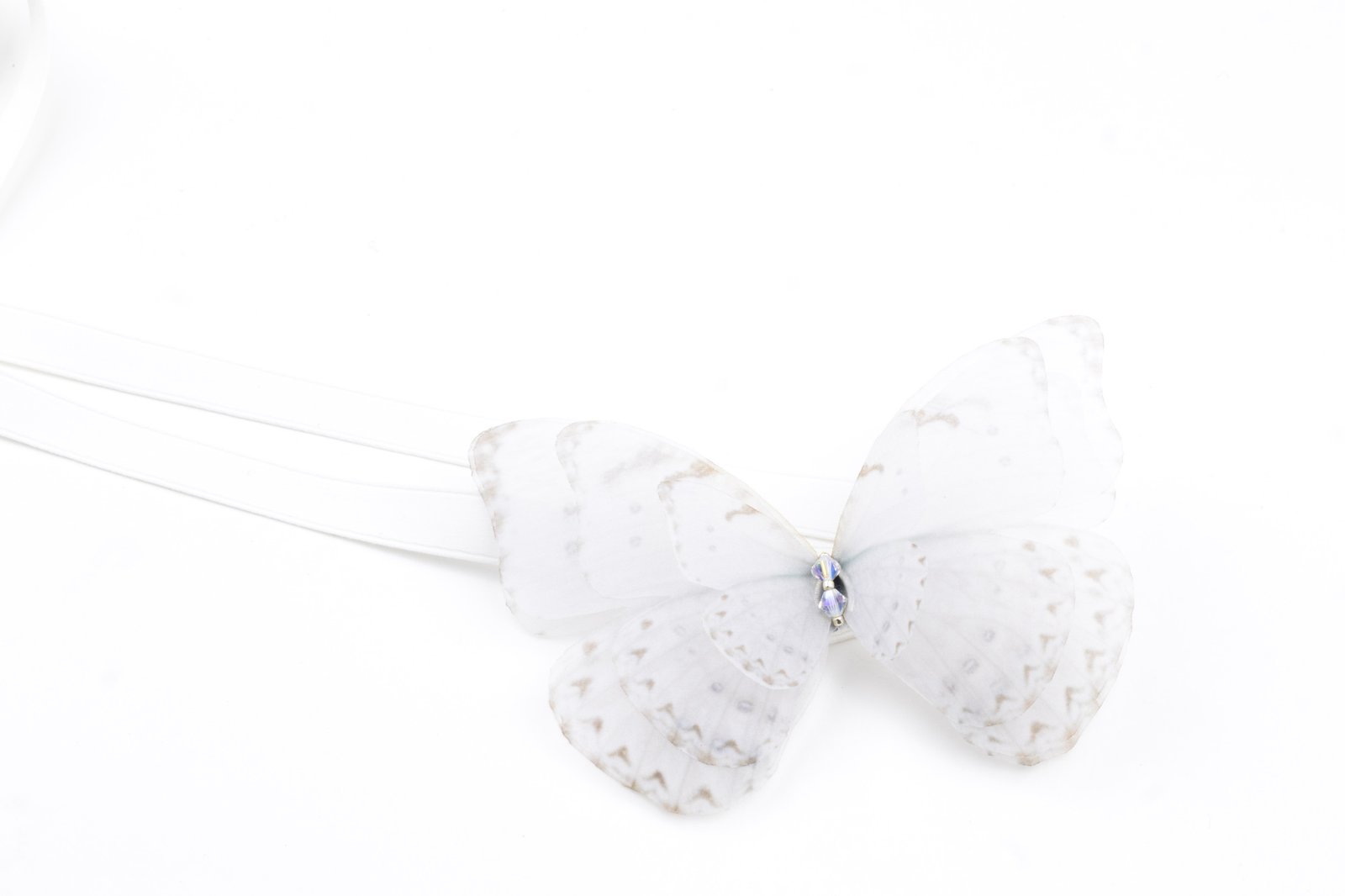 Butterfly Ribbon Tie - Off White Oana Savu This handmade ribbon tie accessory is meticulously crafted with precision, capturing the likeness of a real butterfly. A versatile accessory that can be worn in multiple ways. Whether styled around your neck as a choker necklace or worn adorning the hair, it fastens with a silk ribbon tie, making the fit fully customizable. The white butterfly and ribbon color makes this accessory suitable for a bride as well, plus, it can be successfully worn after the wedding as well, styling your daily outfits with your favorite accessory.