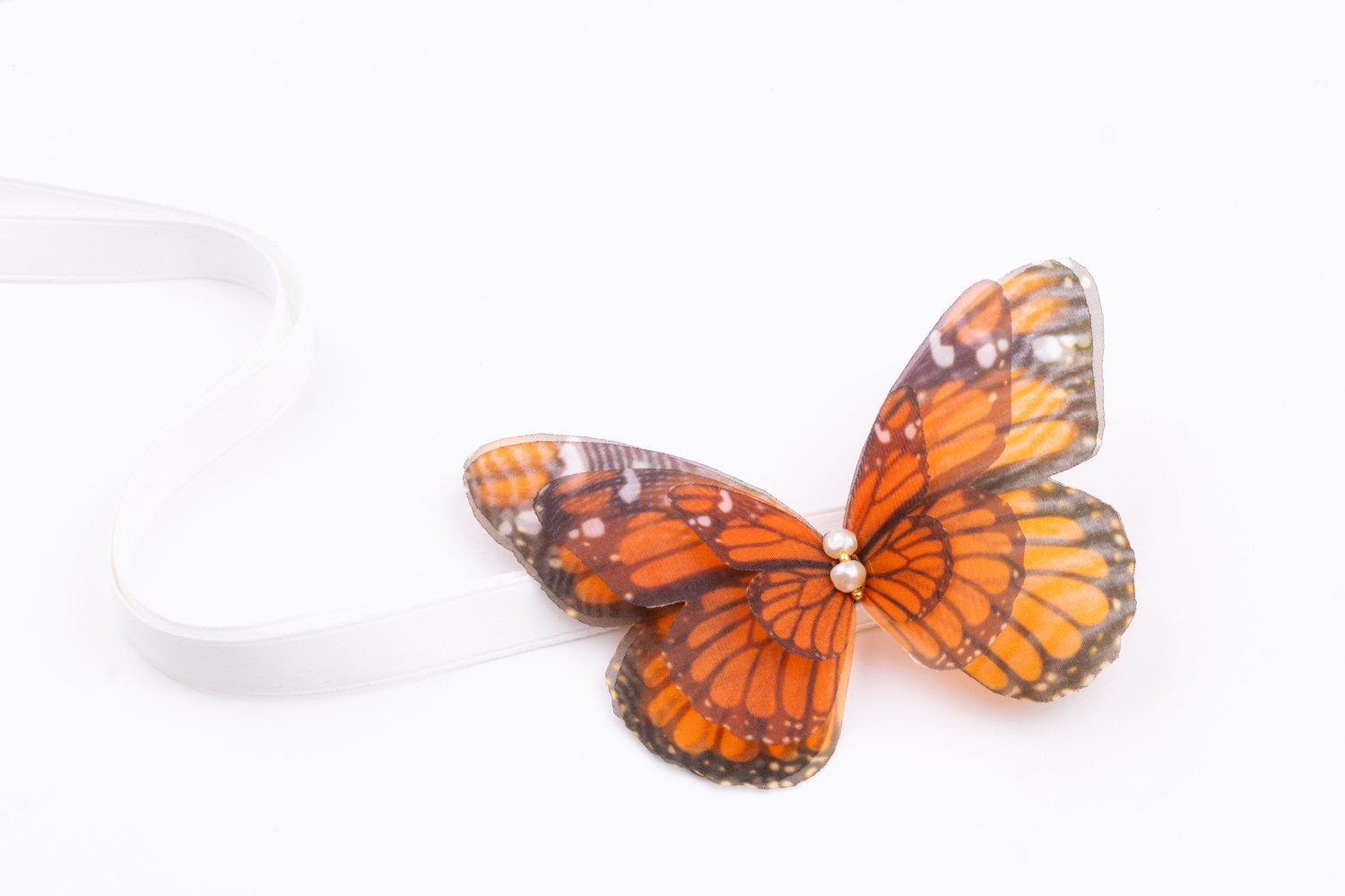 Butterfly Ribbon Tie - Monarch, White Ribbon Oana Savu Handmade ribbon tie accessory is sewn by hand in our little atelier near in Antwerp, Belgium. The voluminous silk butterfly worn around your neck, frames the face, adding a spark of ingenuity to any look. It is sewn on a high-quality silk satin ribbon tie, with a customizable length to fit more styles, worn around your neck - as a choker necklace, style your hair oh hot summer days, around your wrist as a bracelet or even around your waist as a belt for those light summer dresses.
